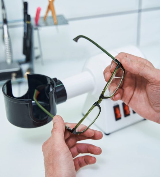 Close up of man optometrist sitting at the table and holding eyeglasses